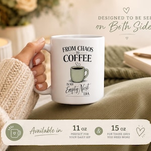 May include: A white ceramic mug featuring a black printed graphic of a light green coffee cup and the text FROM CHAOS TO COFFEE IN MY EMPTY NEST ERA. The mug is held by a hand wearing a beige knit sleeve, with text indicating 11 oz and 15 oz sizes.