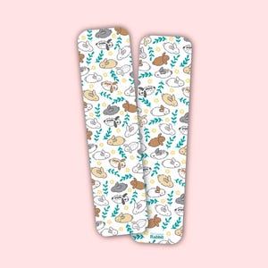 Op de afbeelding: Twee witte kaartjes in de stijl van een bladwijzer met een herhalend patroon van bruine, grijze en witte konijnen met groene bladeren en gele bloemen. De tekst "The Company of Rabbit" staat gedrukt op de onderkant van de rechter kaart.