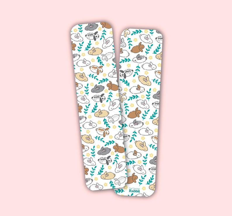 Op de afbeelding: Twee witte kaartjes in de stijl van een bladwijzer met een herhalend patroon van bruine, grijze en witte konijnen met groene bladeren en gele bloemen. De tekst "The Company of Rabbit" staat gedrukt op de onderkant van de rechter kaart.