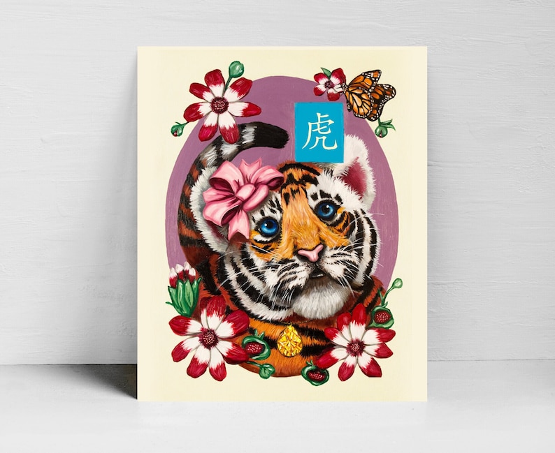 K&ouml;nnte beinhalten: Ein s&uuml;&szlig;es Cartoon-Tigerjunges mit blauen Augen und einer rosa Schleife, umgeben von Blumen. Der Tiger tr&auml;gt eine goldene Halskette und das Bild enth&auml;lt das chinesische Schriftzeichen f&uuml;r "Tiger" in Blau.