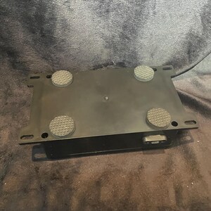 May include: Black rectangular box with four rubber feet on the bottom. The box has a single power cord connection on the side.