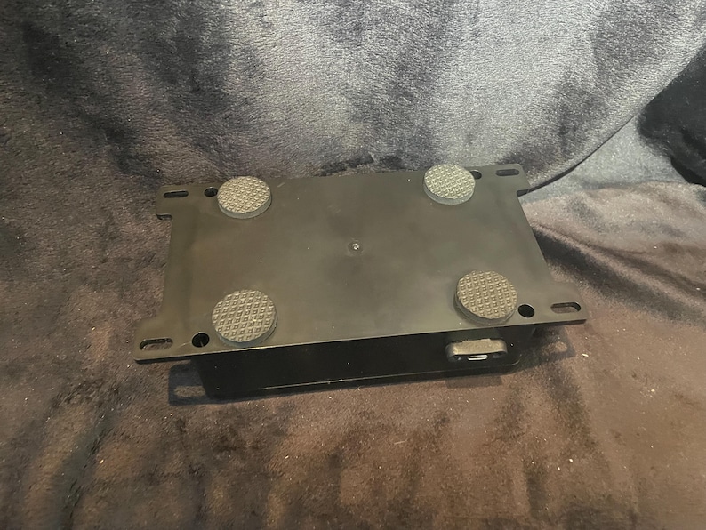 May include: Black rectangular box with four rubber feet on the bottom. The box has a single power cord connection on the side.