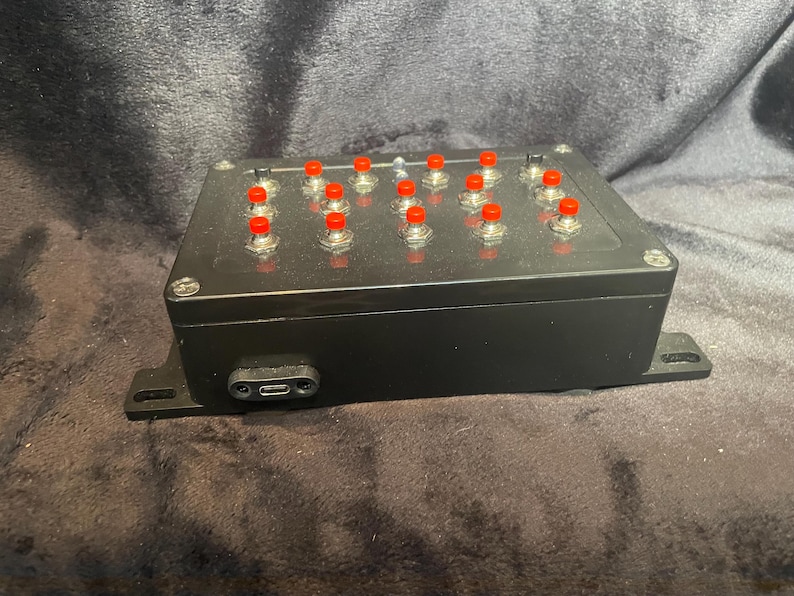 May include: A black box with a row of red buttons. The box has a USB-C port on the side.