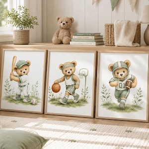Op de afbeelding: Een set van drie ingelijste wandkunstprints met teddyberen in aquarel-stijl in saliegroene en witte sportkleding. De eerste beer speelt honkbal, de tweede basketbal en de derde American football, allemaal afgebeeld tegen een grasachtergrond.