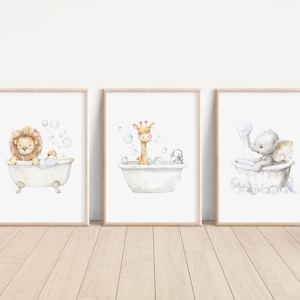 May include: Three framed watercolor prints featuring animals in bathtubs. A lion, giraffe, and elephant are depicted in vintage-style tubs with bubbles. The prints have a light wood frame and are set against a white background.