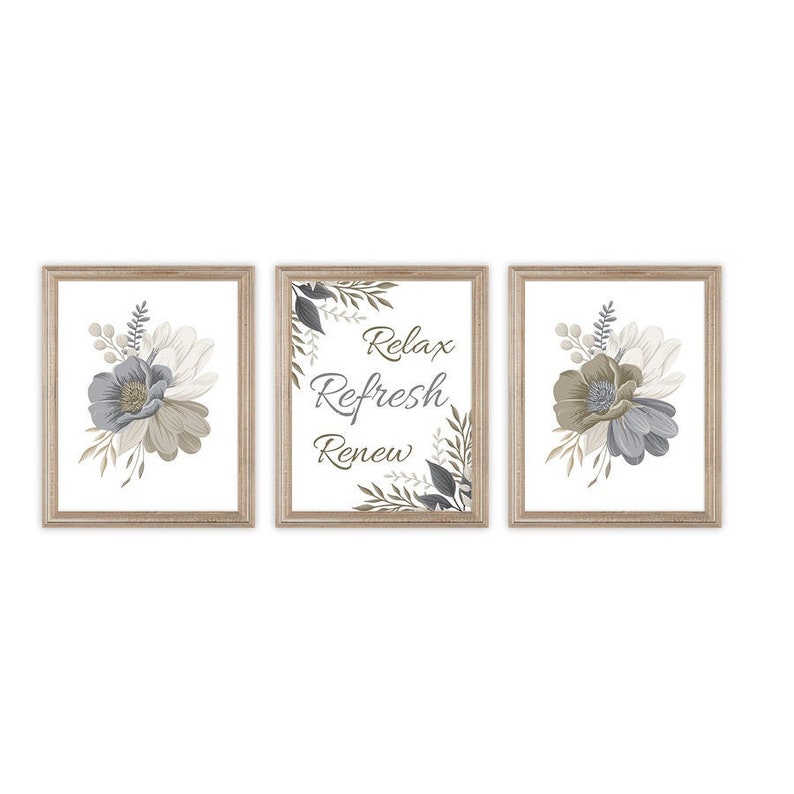 May include: Three framed prints with a floral design and the text "Relax Refresh Renew". The frames are light brown wood and the flowers are a mix of gray and brown.