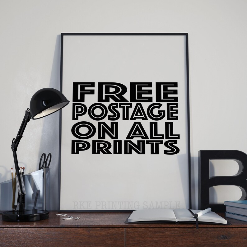以下が含まれることがあります： 白黒のポスターに「FREE POSTAGE ON ALL PRINTS」というテキストが太字で縁取りされた文字で書かれています。ポスターは黒い額縁に収められ、白い壁に掛けられています。