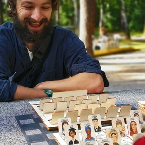 Board game fans. Laughing man in the park playing modern Guess Who made in wood.