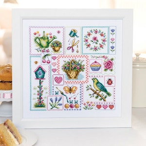 May include: A framed cross-stitch design featuring a patchwork of colorful squares with images of a birdhouse, a basket of flowers, a watering can, a cupcake, a butterfly, and a bird. The design is surrounded by a white frame.