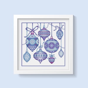 Peut inclure: Une œuvre d'art encadrée en point de croix représentant une collection de boules de Noël stylisées dans des tons de bleu et de violet. Chaque ornement a un motif unique et est suspendu à une ficelle avec un nœud ou des perles. L'œuvre est sur fond blanc.