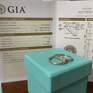 May include: A GIA diamond grading report with a diamond ring in a light blue box. The report shows the diamond is 0.35 carats, H color, VS1 clarity, and Very Good cut. The diamond is round brilliant and measures 4.54-4.59 x 2.82 mm.