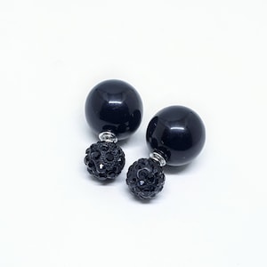 May include: A pair of black double-sided earrings. Each earring features a large black ball with a smaller black ball covered in rhinestones.