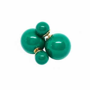 May include: A pair of green, glossy, double-sided ball earrings. The earrings feature a large, round ball on the front and a smaller ball on the back, connected by a gold-colored post. The earrings are set against a white background.