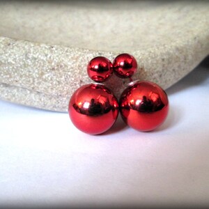 May include: A pair of red double-sided earrings with a shiny, metallic finish.