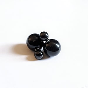 May include: A pair of black double-sided stud earrings with three round black beads.