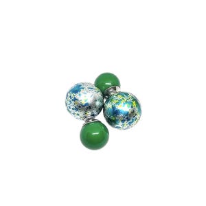 Puede incluir: Un par de pendientes de doble cara con esferas moteadas de verde y azul. Las esferas son plateadas con salpicaduras de pintura verde y azul.
