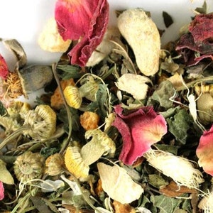 May include: A close-up of a blend of dried herbs and flowers for tea. The mix includes dried rose petals, chamomile flowers, and ginger pieces.