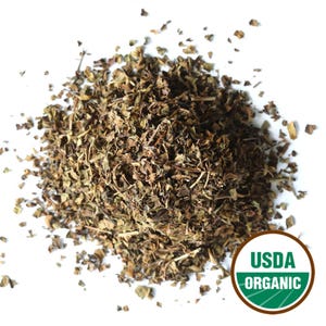 May include: A pile of dried, chopped green herbs, possibly mint or a similar culinary herb, against a white background. A USDA Organic seal is visible in the lower right corner, indicating organic certification.