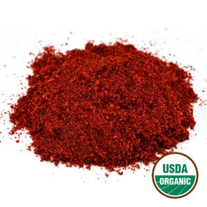 Puede incluir: Un mont&oacute;n de especia roja brillante, finamente molida, probablemente piment&oacute;n o chile en polvo, sobre un fondo blanco. La imagen incluye un sello USDA Organic, que indica la certificaci&oacute;n del producto. La textura de la especia es fina y polvorienta.