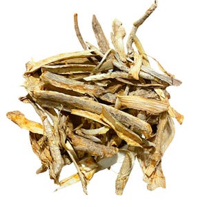 May include: A pile of dried, light brown, and beige plant material. The pieces vary in size and shape, with some appearing like thin, flat strips and others more like small, irregular sticks. The background is plain white.