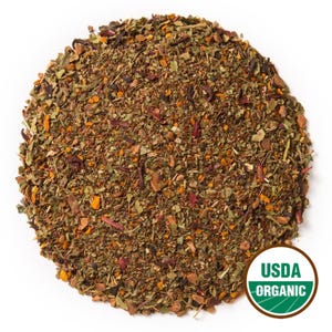Peut inclure: Un tas circulaire de mélange de tisane en vrac composé de morceaux botaniques séchés verts, bruns et rouge foncé. Un sceau rond vert et blanc avec le texte USDA ORGANIC est positionné en bas à droite du mélange de plantes séchées.