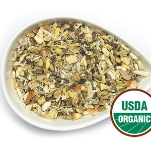 Könnte beinhalten: Eine weiße Schüssel gefüllt mit einer Mischung aus getrockneten Kräutern und Gewürzen, darunter Ingwer, Süßholzwurzel und andere Pflanzen. Die Schüssel steht auf weißem Hintergrund. Das USDA Organic Siegel ist in der unteren rechten Ecke sichtbar.