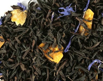 May include: Close-up of black tea leaves with orange and blue pieces. The tea blend includes black tea, orange peel, and cornflower petals.