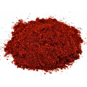Puede incluir: Un mont&oacute;n de piment&oacute;n rojo vibrante y finamente molido sobre un fondo blanco. La especia parece reci&eacute;n molida, con una textura ligeramente gruesa. La imagen es un primer plano, que destaca el color y la textura ricos del piment&oacute;n.