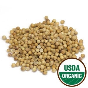 May include: A close-up view of a pile of light brown coriander seeds. The seeds are small and round, with a slightly wrinkled texture. The USDA Organic seal is visible in the lower right corner of the image.