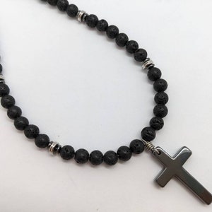 May include: A black lava rock beaded necklace with silver accents and a black cross pendant.