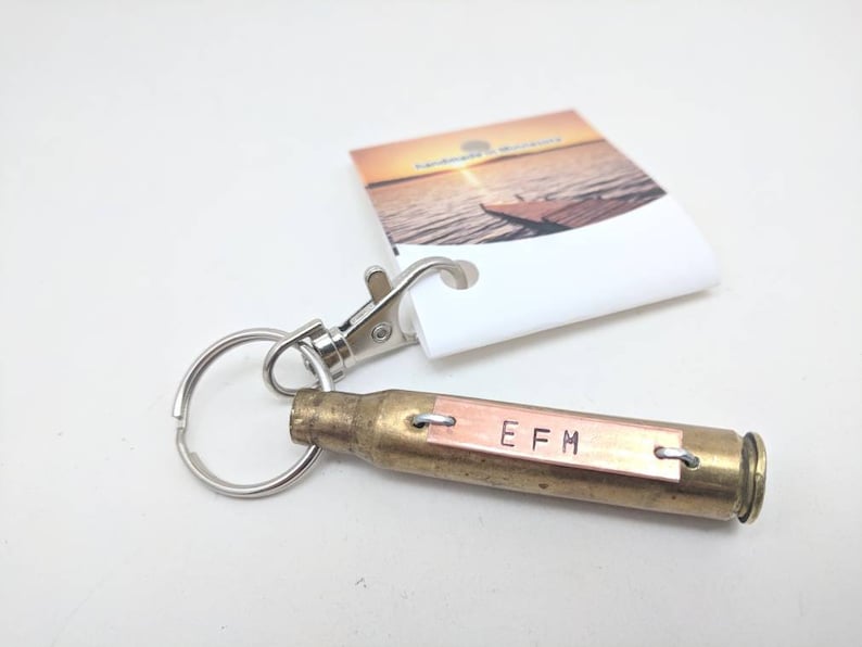 keychain made with recycled brass shell casing from memorial salute, this example shows initials EFM in uppercase Ariel font. the casing is brass and the plate is copper. each unique piece is hand-pounded on an anvil for an imperfect hand made feel