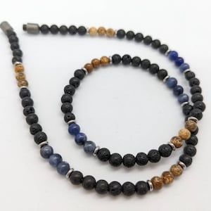 May include: A beaded necklace with black lava rock, brown jasper, and blue lapis lazuli beads.