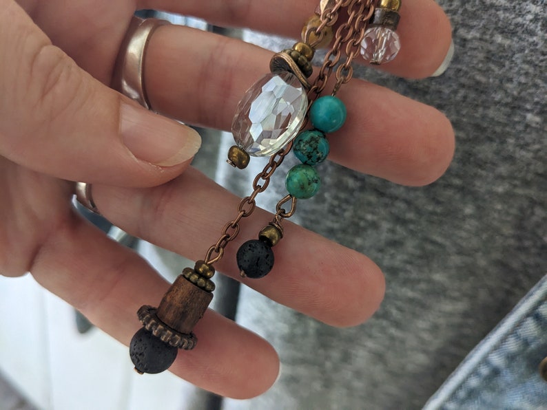 Closeup of long boho pendant. 8mm lava bead, 6mm lava, 6mm turquoise and glass crystal charms by JT Maui Designs