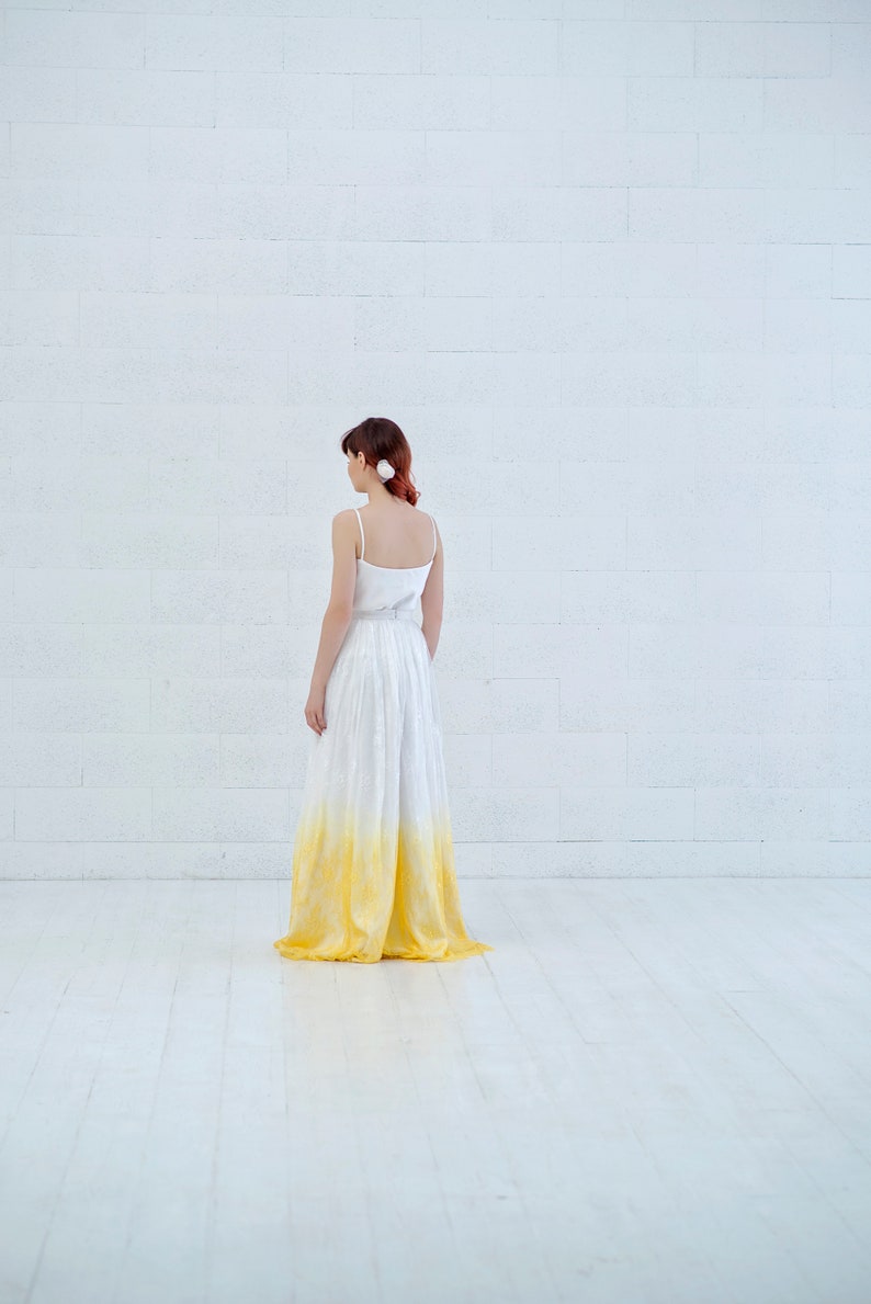 May include: A white maxi skirt with a yellow ombre effect. The skirt is made of a lightweight fabric and has a flowy silhouette.