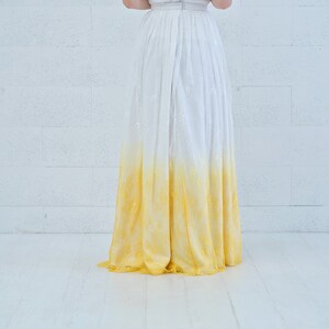 May include: A white and yellow ombre wedding dress with a lace skirt.