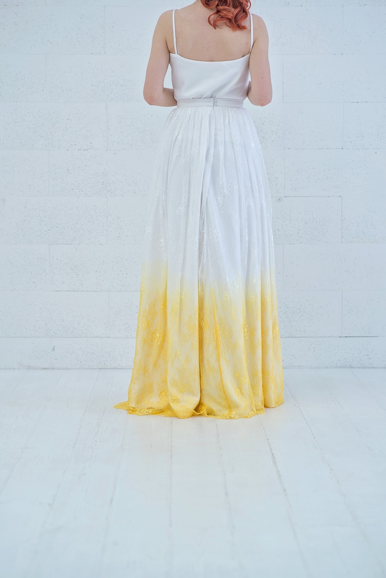 May include: A white and yellow ombre wedding dress with a lace skirt.