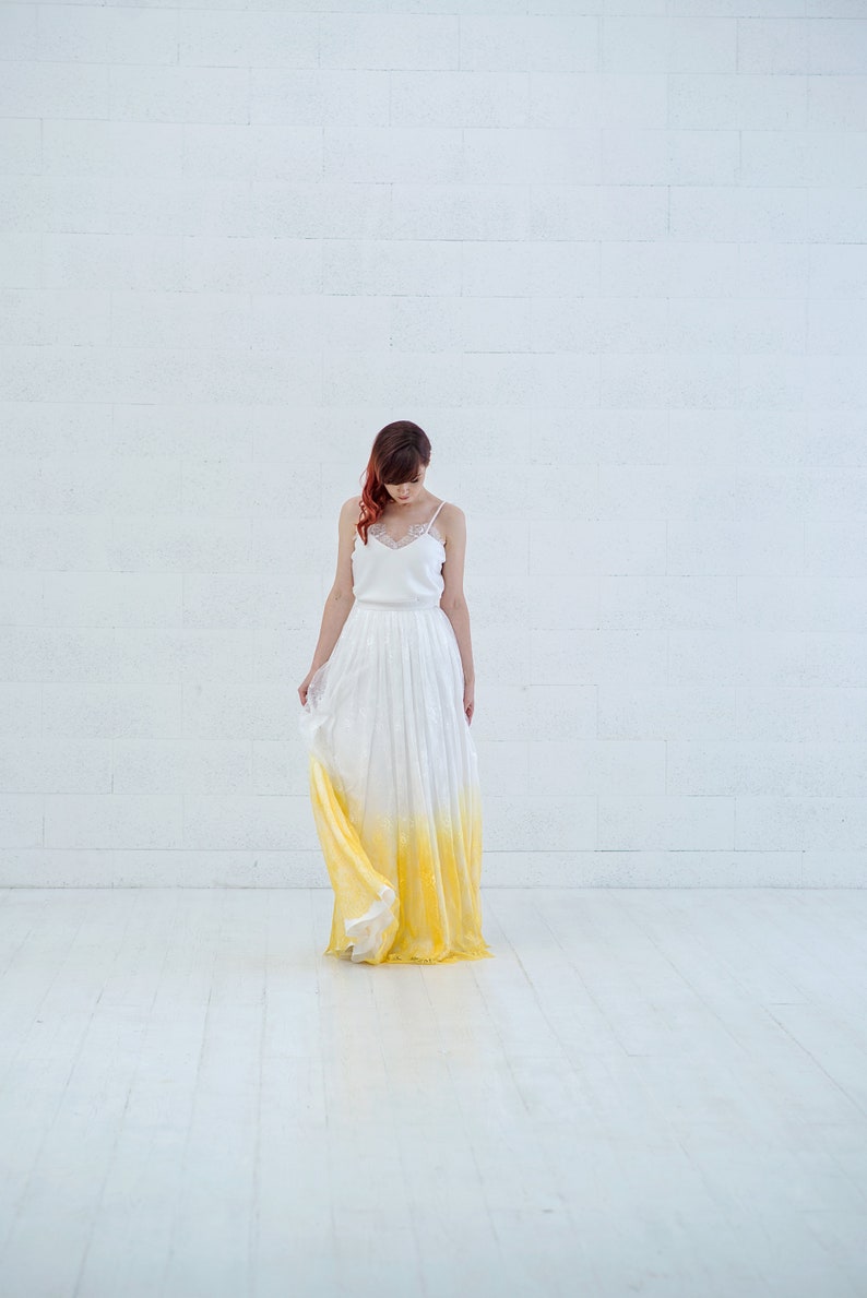 May include: A woman wearing a white and yellow ombre wedding dress with a lace bodice.