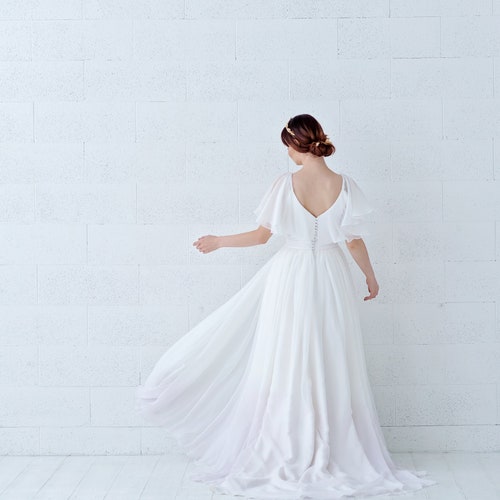 Robe de mariée en mousseline de soie avec manches cape, bas et poches teints dans la masse