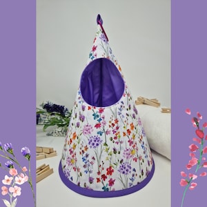 Könnte beinhalten: Eine konische, hängende Aufbewahrungstasche in Lila und Weiß mit einem Blumenmuster. Die Tasche hat ein lilafarbenes Futter und eine Schlaufe oben zum Aufhängen.