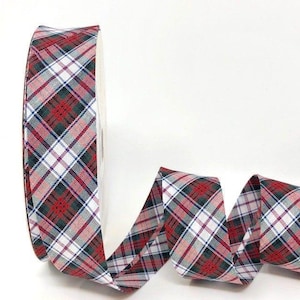 May include: A roll of plaid ribbon in red, white, green, and navy blue. The ribbon has a classic tartan pattern, with intersecting lines creating a checkered design. The ribbon is likely used for crafting, gift wrapping, or holiday decorations.