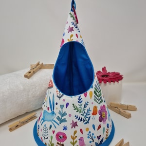 May include: A white cone-shaped hanging organiser with a blue lining and a colourful floral print featuring birds, rabbits, and flowers. The organiser has a blue trim and a loop at the top for hanging.