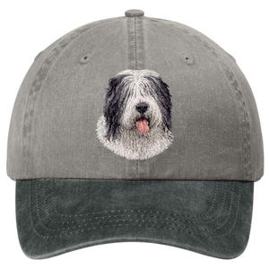 May include: A gray baseball cap with a dark gray bill. The cap features an embroidered image of a Bearded Collie dog with black and white fur and its tongue sticking out. The cap has a curved brim and an adjustable strap.