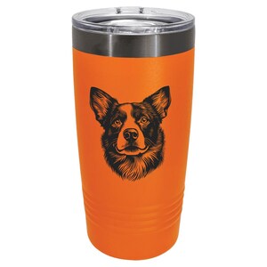 May include: An orange insulated tumbler with a black and white illustration of a dog's face. The tumbler has a stainless steel rim and a clear plastic lid. The dog illustration is centered on the tumbler.
