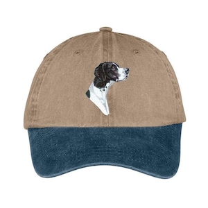 May include: A brown and blue baseball cap with an embroidered image of a black and white English Pointer dog on the front.