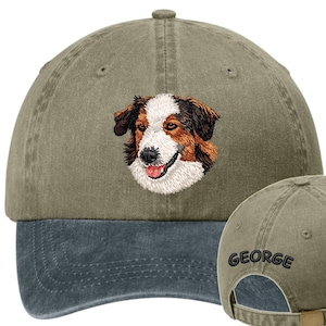 May include: A two-tone baseball cap with a dog portrait embroidered on the front. The cap features a green-gray crown and a dark blue bill. The dog's face is detailed with brown, white, and black thread. The name "GEORGE" is embroidered on the back.