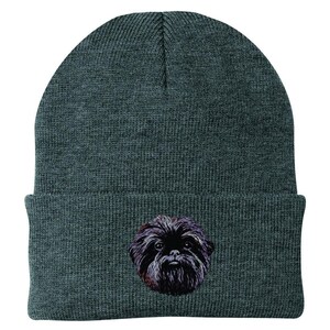May include: A dark gray beanie featuring an embroidered image of a black Shih Tzu dog. The beanie is made of a knitted material and has a folded cuff. The dog's face is detailed with black and brown fur.