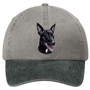 May include: A gray baseball cap with a dark gray brim featuring an embroidered graphic of a black dog with pointed ears, brown eyes, and an open mouth with a pink tongue visible. The dog has a small white patch of fur on its chest area.