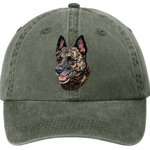May include: A green baseball cap featuring an embroidered image of a dog's head. The dog has brown and black fur with a pink tongue. The cap has a curved brim and an adjustable strap.