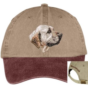 May include: A tan and maroon baseball cap with an embroidered image of a light brown dog's head. The back of the cap has the word "Moonstruck" embroidered in brown.