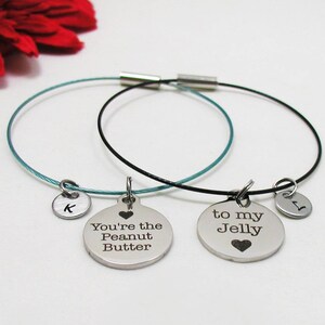 May include: Two silver bracelets with charms. One charm says "You're the Peanut Butter" and the other says "To my Jelly".